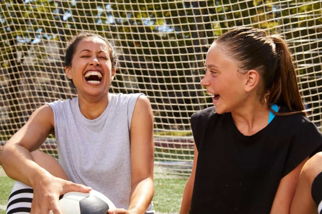 Teen girl on a soccer field laughing with her mentor