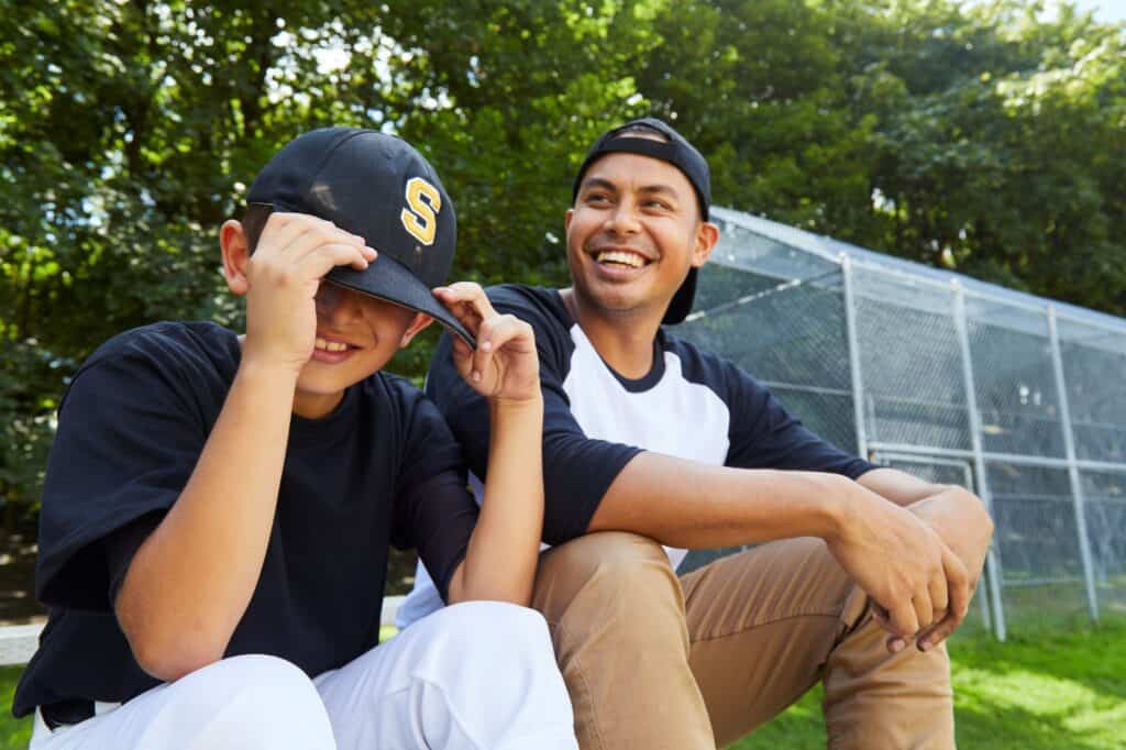 Mentor smiling with his mentee on a baseball field