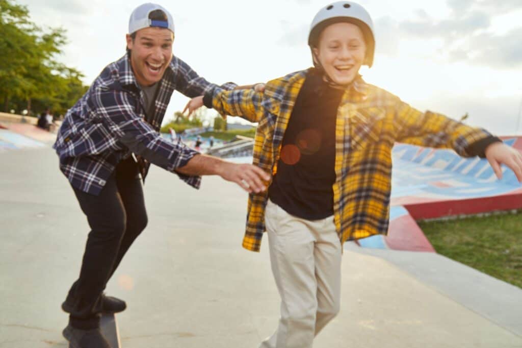 Young boy skateboarding with his mentor