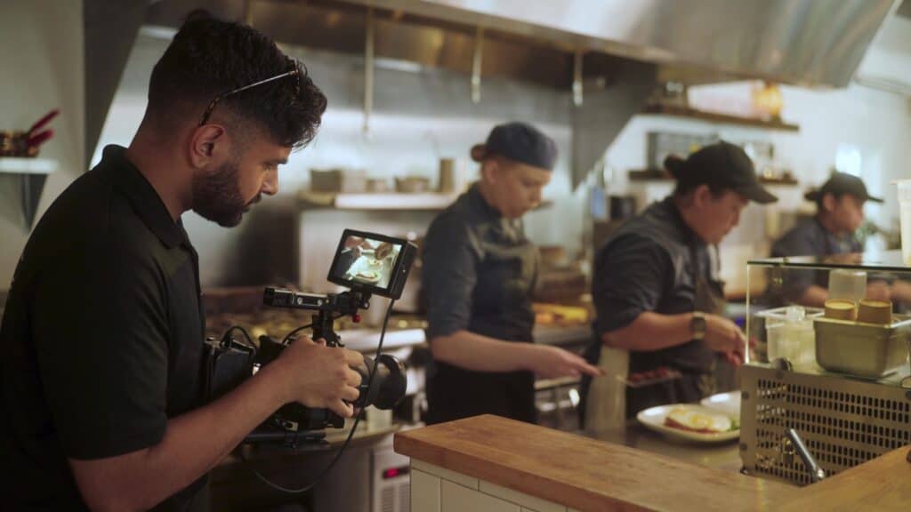 Candid shot of Geet filming cooks in a kitchen